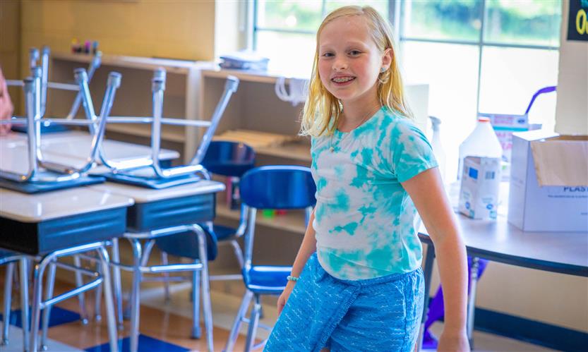 A girl wearing a light blue shirt smiles
